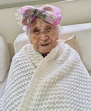 imagem de uma senhora rindo com um cobertor branco e um lenço na cabeça florido na casa de repouso mamma mia imagem de uma senhora rindo com um cobertor branco e um lenço na cabeça florido na casa de repouso mamma mia
